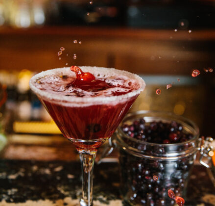 Cocktail glass liberally filled with cheery splashing into the drink