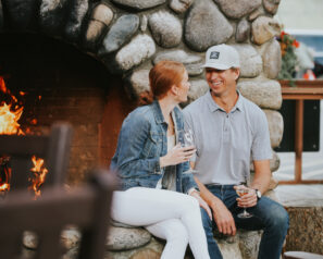 Couple sitting next to a large stone fireplace