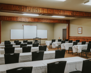 a large meeting room full of tables and chairs with a projector and screen at the front of the room