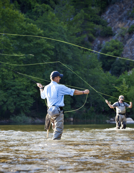 Two men standing in a stream fly fishing
