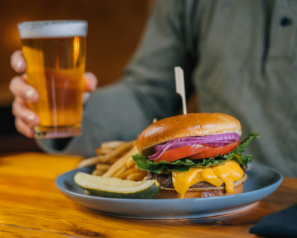 A cheeseburger with fresh vegetables, fries and a beer