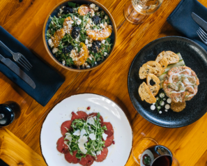 Overhead view of three delicious dishes, with place settings and wine