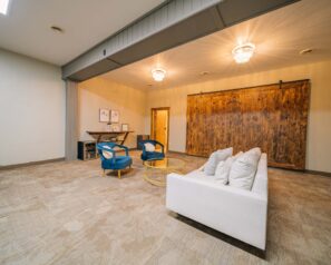 A large room with a large white sofa and two modern, blue velvet lounge chairs