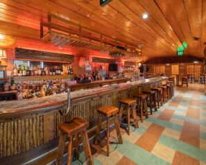A rustic bar with heavy wooden bar stools and ambient lighting