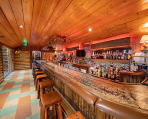 A rustic bar with heavy wooden bar stools and ambient lighting