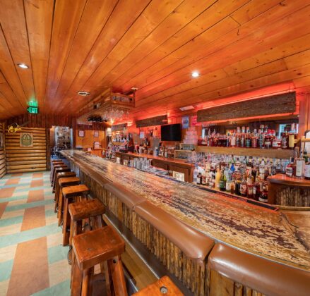 A rustic bar with heavy wooden bar stools and ambient lighting